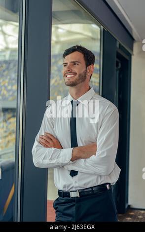 Foto verticale dell'uomo d'affari in camicia bianca in piedi accanto alla finestra Foto Stock