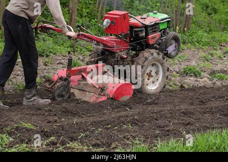 Uomo agricoltore che lavora in campo arando terra con aratro in fattoria. Terreno di lavorazione stagione in villaggio. Coltivare prodotti naturali biologici. Foto Stock