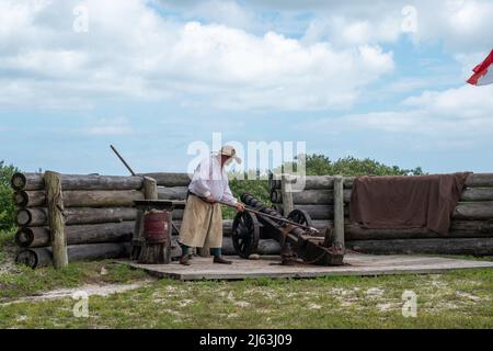 Un maschio bianco che indossa panni in stile spagnolo sparando un cannone in una rievocazione storica Foto Stock