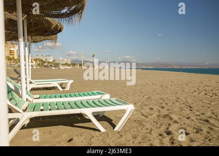 Sedie a sdraio vuote sulla sabbia sul litorale di fronte al mare Foto Stock