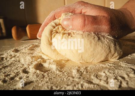 Preparare l'impasto per il pane, impastando l'impasto con le mani sul tavolo. Foto Stock