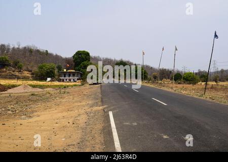 Strada autostradale sul ghat zona di montagna nella foresta a madhya pradesh con linea bianca marcatura su entrambi i lati della strada e alberi secchi. Negozio di pneumatici vicino al motel ON Foto Stock