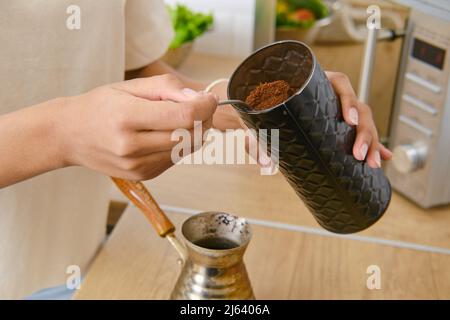 Primo piano vista delle mani che fanno caffè macinato a casa in cezve turco Foto Stock