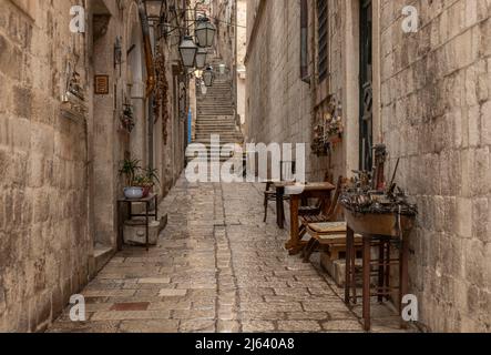 Guardando su un vicolo di Dubrovnik verso ripido gradino con vari manufatti fuori dalle porte Foto Stock