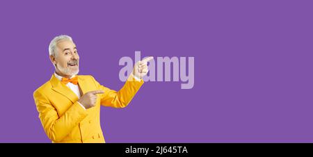 Bell'uomo di mezza età che punta via di lato con il suo dito isolato sfondo viola. Spase per la vostra pubblicità. Foto Stock