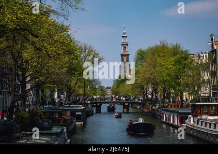 AMSTERDAM, PAESI BASSI - 23 APRILE 2022: Immagine dell'Westertoren della Chiesa Ovest di Amsterdam con un canale in primo piano in una giornata di sole Foto Stock