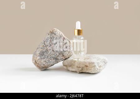 Bottiglia di vetro in piedi sulla pietra. Naturale cura della pelle SPA bellezza prodotto design. Prodotti cosmetici a base di olio minerale biologico su sfondo beige. Simulazione. Foto Stock