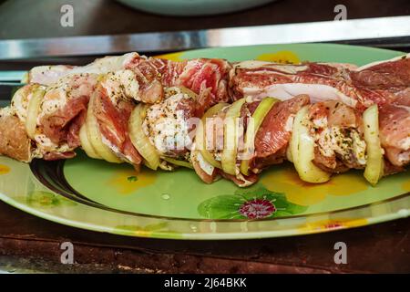 Carne marinata cruda e cipolla su uno spiedino. Il kebab è preparato per cucinare a fuoco aperto. Foto Stock