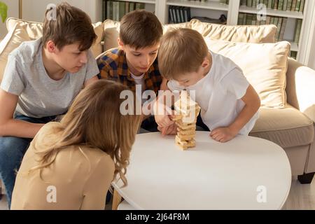 Una donna e tre ragazzi stanno giocando con entusiasmo un gioco da tavolo fatto di blocchi rettangolari di legno Foto Stock