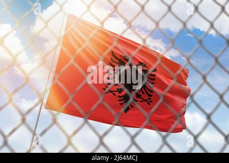 Una rete d'acciaio sullo sfondo di un cielo blu e un flagpole con la bandiera dell'albania Foto Stock