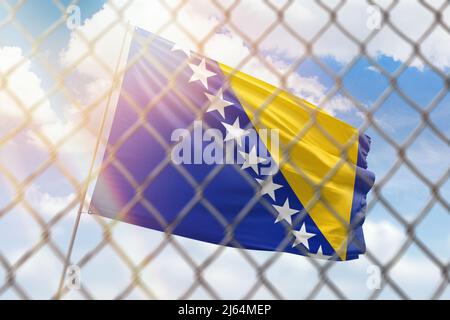 Una rete di acciaio sullo sfondo di un cielo blu e un flagpole con la bandiera della bosnia Foto Stock