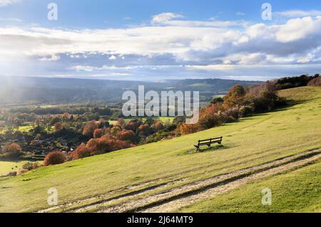 Lone panchina sulle pendici erbose di Colley Hill con vista della campagna Surrey Hills in autunno sole, Reigate, North Downs Way, Surrey, Inghilterra, REGNO UNITO Foto Stock