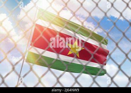 Una maglia di acciaio sullo sfondo di un cielo blu e un flagpole con la bandiera del suriname Foto Stock