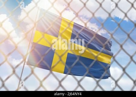 Una rete d'acciaio sullo sfondo di un cielo blu e un flagpole con la bandiera della svezia Foto Stock