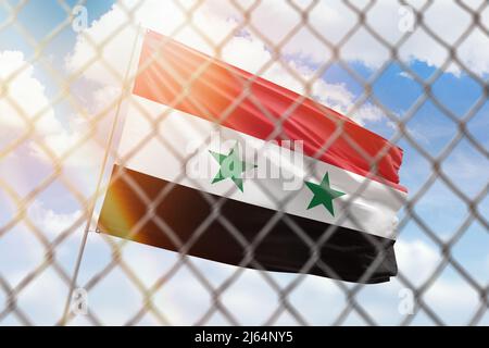 Una rete di acciaio sullo sfondo di un cielo blu e un flagpole con la bandiera della siria Foto Stock