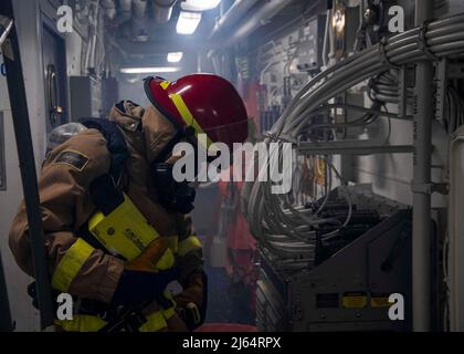 OCEANO INDIANO (26 aprile 2022) danni Controlman Fireman Ethan Cole valuta l'area durante un'esercitazione di controllo danni a bordo del cacciatorpediniere missilistico guidato USS Gridley (DDG 101) nell'Oceano Indiano, aprile 26. Gridley è schierata nell'area operativa della flotta USA 5th per contribuire a garantire la sicurezza e la stabilità marittima nella regione del Medio Oriente. (STATI UNITI Foto Navy di Mass Communication Specialist 2nd Classe Colby A. Mothershead) Foto Stock