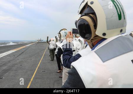 PHILIPPINE SEA (23 aprile 2022) distinti visitatori osservano le operazioni di volo sul ponte di volo del vettore aereo di classe Nimitz USS Abraham Lincoln (CVN 72). Abraham Lincoln Strike Group è in fase di implementazione pianificata nell'area delle operazioni della flotta USA 7th per migliorare l'interoperabilità attraverso alleanze e partnership, fungendo da forza di risposta pronta a supportare una regione indopacifica libera e aperta. (STATI UNITI Foto Navy di Mass Communication Specialist 3rd Classe Javier Reyes) Foto Stock