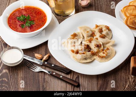 Piatto tradizionale ucraino vareniki e borscht servito con verdure e panna acida. Vista ravvicinata del cibo tradizionale ucraino. Foto Stock