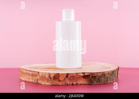 Detersivo, ammorbidente o sapone liquido sul podio rotondo in legno. Presentazione del mockup detergente su sfondo rosa. Liquido sanitario domestico per Foto Stock