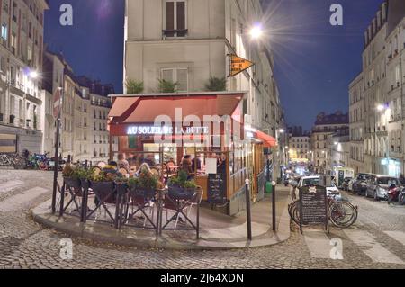 Parigi, Francia - 12 novembre 2021: Strade antiche di Montmartre di notte a Parigi, Francia. I parigini e i turisti godono di cibo e bevande alla strada Foto Stock