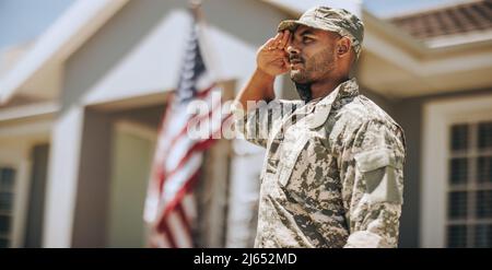 Giovane soldato patriottico che saluta mentre si alza fuori casa. Membro del corpo Marino degli Stati Uniti che mostra onore e rispetto per la Giornata dei Veterani. Foto Stock