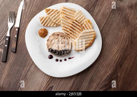 Patata di carne di fegato spalmata con pane bianco alla griglia su sfondo di legno, colazione, primo piano, nessuna gente, fuoco selettivo, pasticcio, pastete. Foto Stock