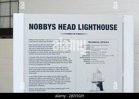 Un cartello che spiega la storia del faro di Nobbys, situato all'ingresso del porto di Newcastle, che è stato illuminato per la prima volta nel 1858 Foto Stock