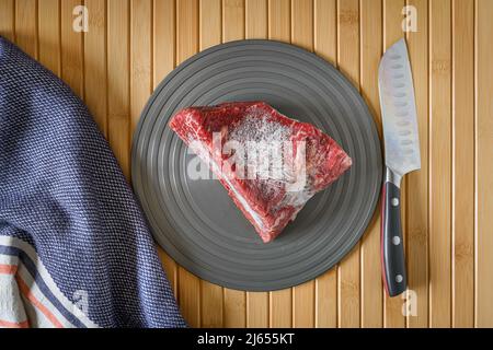 Pezzo di manzo Wagyu su un piatto con tappeto di bambù come sfondo Foto Stock