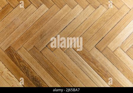 Parquet in legno naturale a spina di pesce. Pavimenti in legno di quercia dettaglio sfondo. Vecchio asse decorativo marrone, motivo ripetuto. Interno casa, t Foto Stock