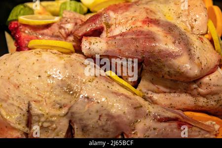 Gamba di agnello con osso crudo con patate e erbe in teglia da forno. Preparazione di cibo tradizionale greco pasquale, carne di capra marinata o di pecora con ve fresche Foto Stock