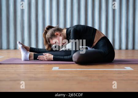 La donna si inclina in avanti allunga la schiena e le gambe Foto Stock