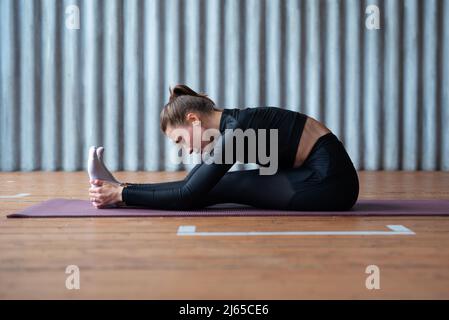 La donna si inclina in avanti allunga la schiena e le gambe Foto Stock