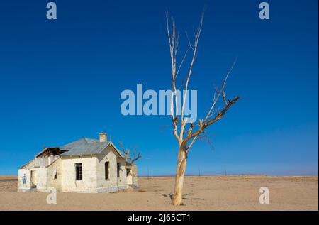 L'ex stazione ferroviaria si è sgretolata in una zona solitaria di Garub, nel sud della Namibia, in Africa. Si tratta di un edificio bianco vuoto e dilapidato, con sabbia deserta Foto Stock