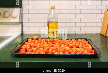 Pomodori d'uva invernali arrostiti in una padella per preparare la salsa di pasta fresca. I pomodori grappoli d'Inverno raccolti in ottobre dureranno fino all'inverno. Foto Stock