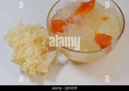 Zuppa da dessert di neve bollita o fungo bianco con papaia in ciotola di vetro con Tremella fuciformis secca, su bianco Foto Stock