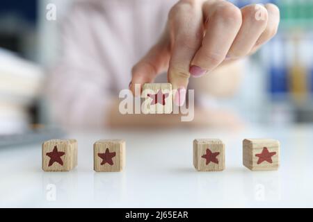 Mani del cliente che tiene cubo di legno blocco con cinque stelle voto Foto Stock