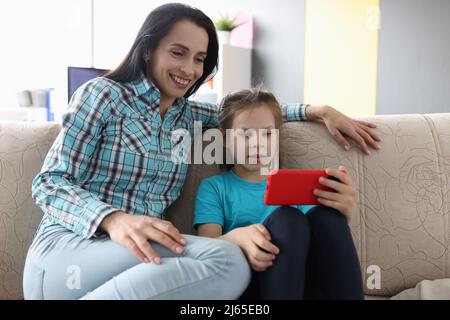 Mamma con la figlia che comunica con i parenti tramite videochiamata Foto Stock