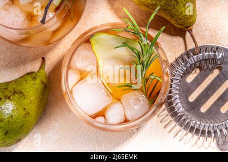 Bevanda alcolica fruttata, dolce pera fredda con rum, liquore, anice e rametto rosmarino, guarnito con pera affettata Foto Stock