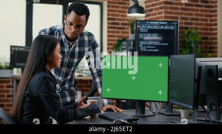 Team misto di programmatori che analizzano il codice sorgente guardando il mockup chiave chroma schermo verde che discute l'algoritmo. Sviluppatori di app che lavorano al cloud computing online nella sala server. Foto Stock