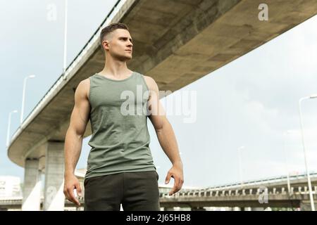 Giovane atletico che indossa abbigliamento sportivo cachi dopo il suo allenamento di strada Foto Stock
