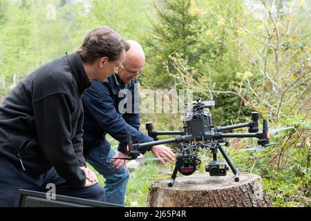 Bonn, Germania. 26th aprile 2022. Da destra: Il Prof. Dr. Alexander Asteroth, Bonn Rhein Sieg University of Applied Sciences, presenta il suo programma per la registrazione dei danni alla foresta causati dai droni, Hendrik WUEST, Wust, CDU, primo Ministro del Nord Reno-Westfalia, primo Ministro Henrik WUEST in una visita al Kottenforst sulla situazione e il futuro della foresta, credito: dpa/Alamy Live News Foto Stock