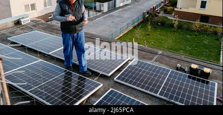 Il tecnico controlla la configurazione del pannello solare. Utilizzo di smart app nel tablet Foto Stock