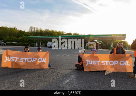 Kent, Regno Unito. 28 aprile 2022 i manifestanti di Just Stop Oil hanno bloccato il garage BP presso Clacket Lane Services il M25. Essi chiedono al governo di porre fine all’estrazione di nuovi combustibili fossili e alla perforazione di gas e petrolio, esortandoli invece a investire in energie rinnovabili. I manifestanti smash il vetro su pompe a benzina e graffiti sulla parte anteriore, infine incollandosi alle pompe credito: Denise Laura Baker/Alamy Live News Credit: Denise Laura Baker/Alamy Live News Foto Stock