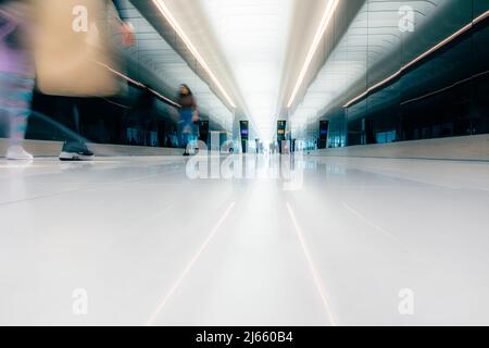 I viaggiatori di fretta camminano fino al cancello di partenza attraverso la luminosa sala dell'aeroporto, l'aeroporto di Stansted Foto Stock