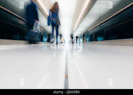 I viaggiatori di fretta camminano fino al cancello di partenza attraverso la luminosa sala dell'aeroporto, l'aeroporto di Stansted Foto Stock