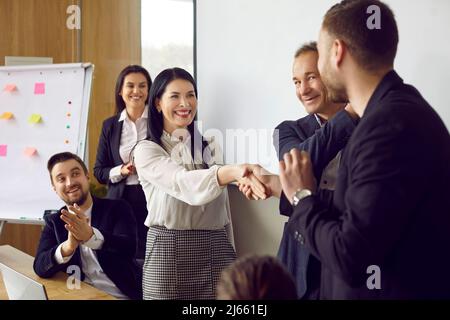 L'uomo e la donna scuotono le mani e sorridono mentre si salutano a vicenda in un incontro d'affari Foto Stock