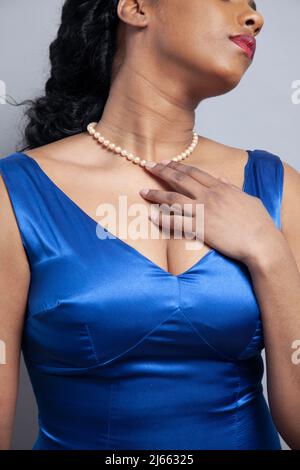 Donna con perle in abito satinato blu Foto Stock