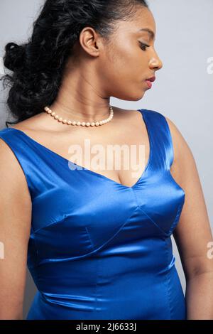 Donna con perle in abito satinato blu Foto Stock