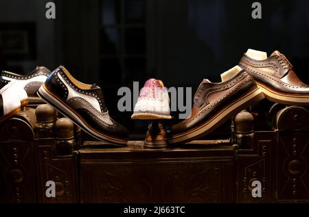 Scarpe con suole in gomma in un deposito di un laboratorio calzolaio, in piedi su un'antica scatola per la cura delle scarpe. Foto Stock