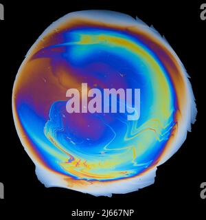 Colori di interferenza da una pellicola di olio su acqua isolata su sfondo nero Foto Stock